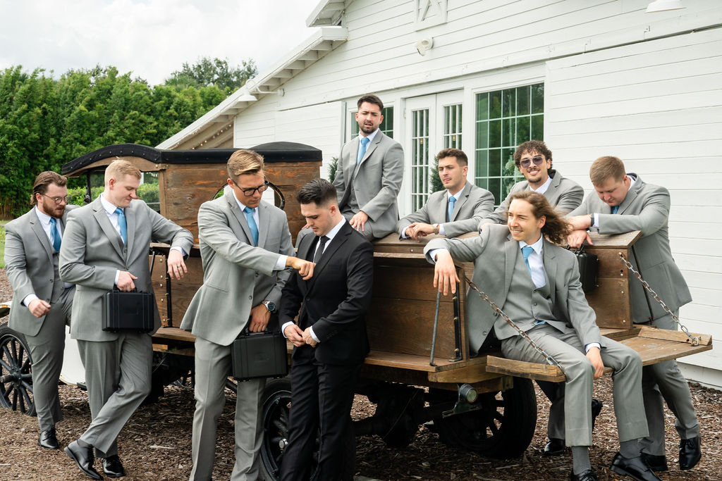 Groom and groomsmen posing together around an outdoor piano