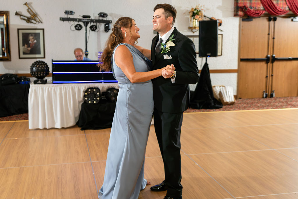 Groom dancing with a woman in a blue formal gown at the reception