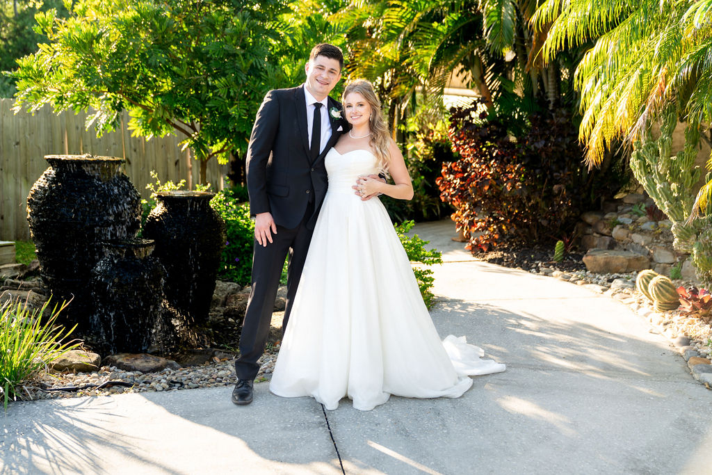 Bride and groom standing beside lush plants on a garden path