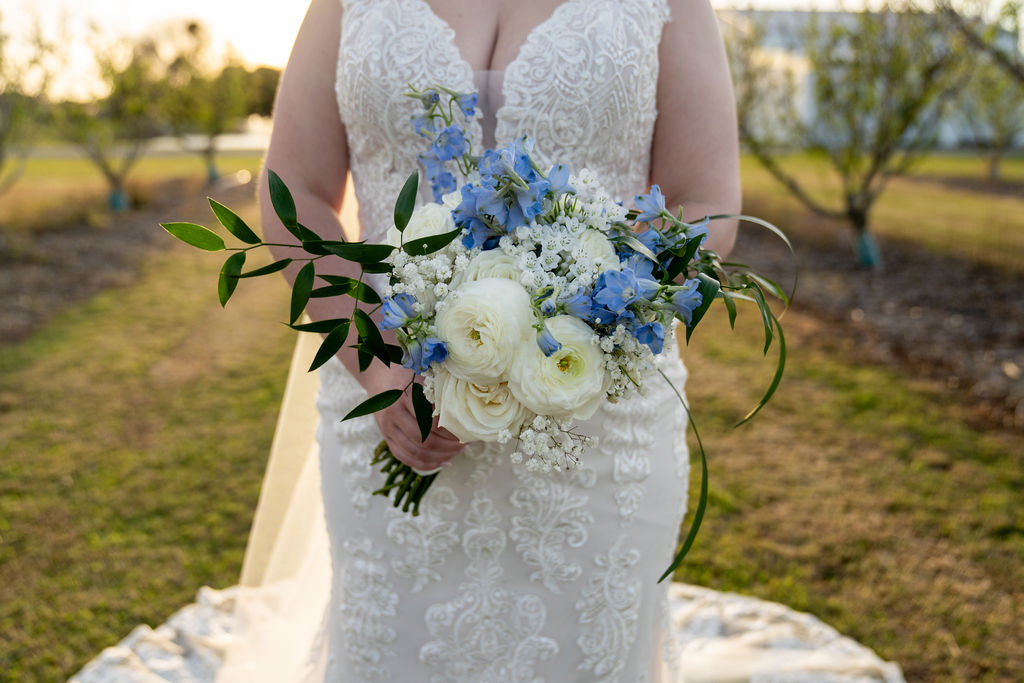 Bride holding a bouquet of white roses and blue flowers