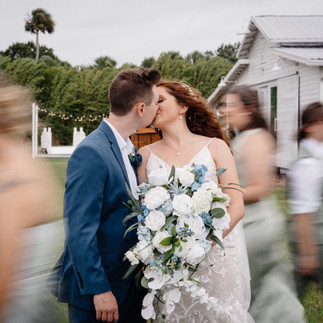 Bride and groom kissing with motion blur of guests walking around them
