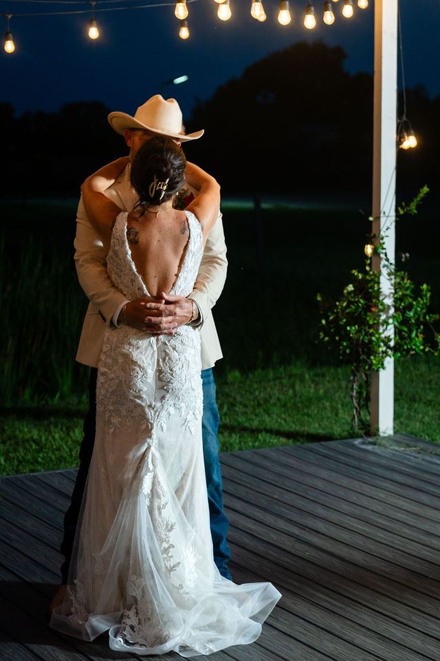 Bride and groom dancing beneath outdoor string lights