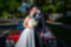 Wedding couple kissing by a red vintage car