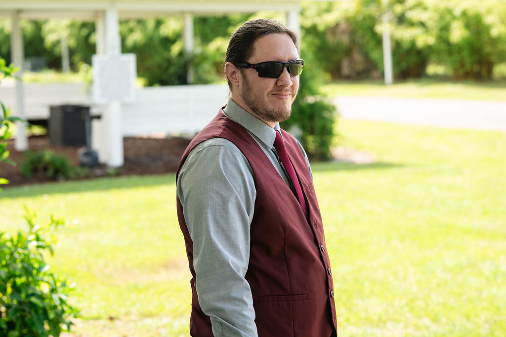 Groom in sunglasses and a burgundy vest outdoors
