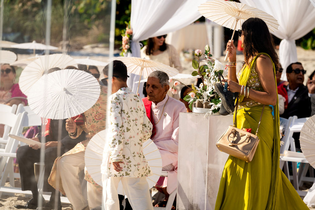 Guests gathered beneath white draping at an oceanfront ceremony