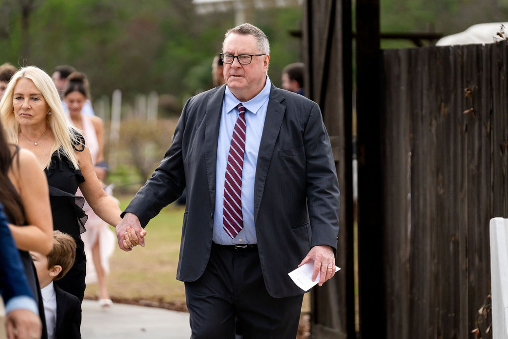 Adult guests walking toward an outdoor wedding ceremony