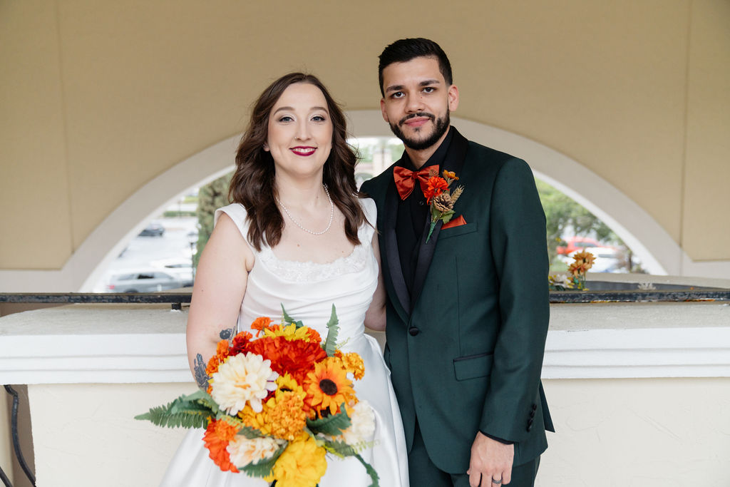 Bride and groom posing together with a colorful autumnal bouquet