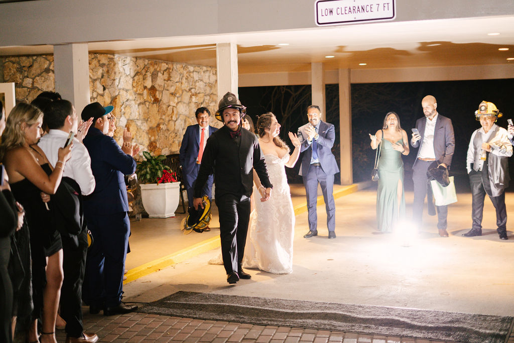Bride and groom walking out of the venue as guests celebrate
