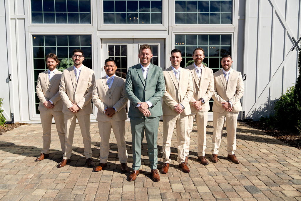 Groom and groomsmen in sage and cream suits outside the venue
