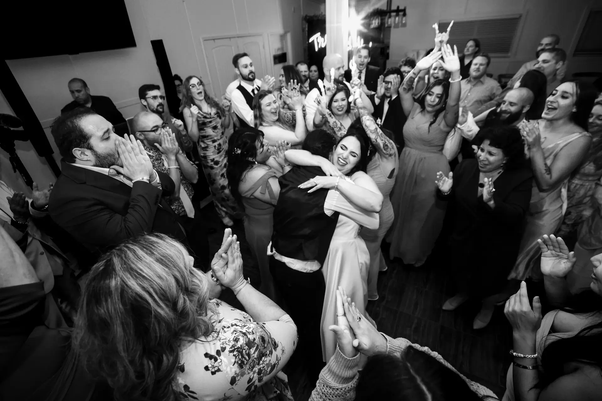 Wedding guests cheering and celebrating together on a crowded dance floor during reception