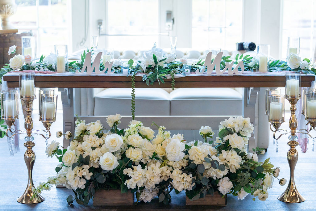 Decorated wedding head table in a bright barn reception room