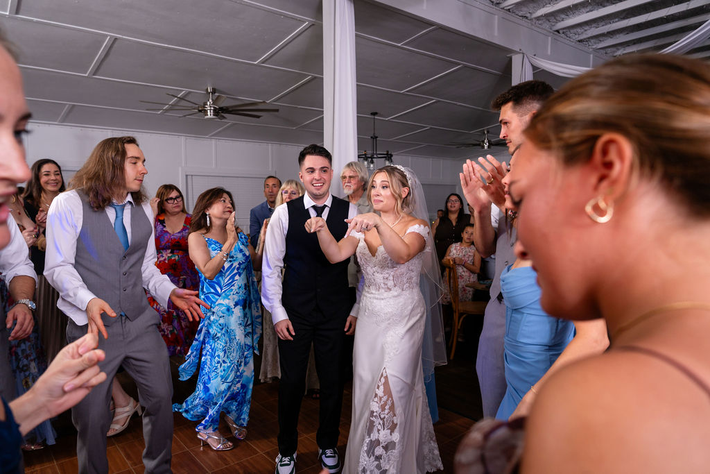 Bride and groom celebrating with guests on the reception dance floor