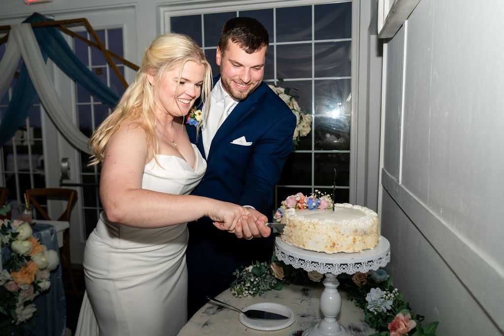 Bride and groom cutting a round wedding cake together