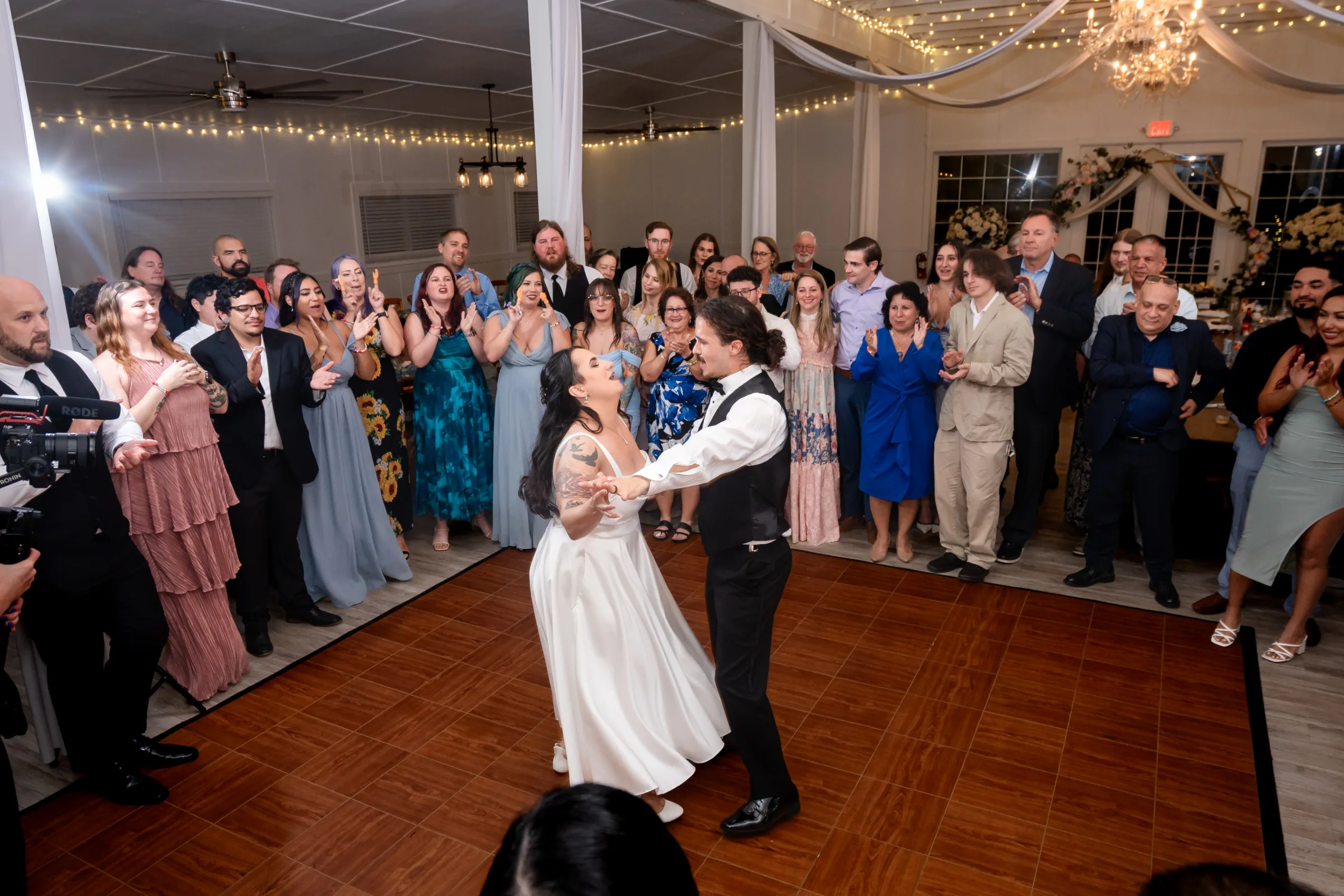 Newlyweds sharing their first dance while wedding guests watch and celebrate around them