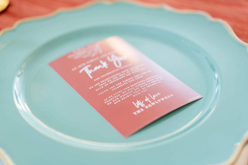 Coral wedding menu card on a pale blue place setting