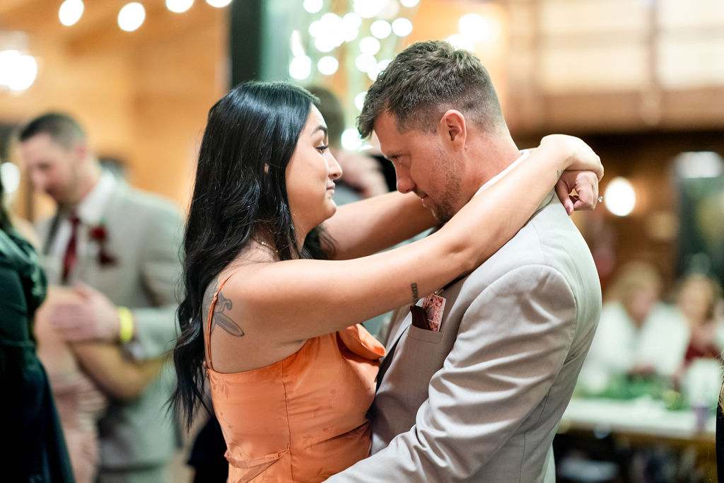 Adult wedding guests embracing while dancing at the reception