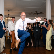 Wedding guest dancing energetically on reception dance floor surrounded by cheering guests