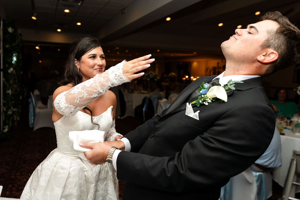 Bride playfully feeding cake to the groom at the wedding reception