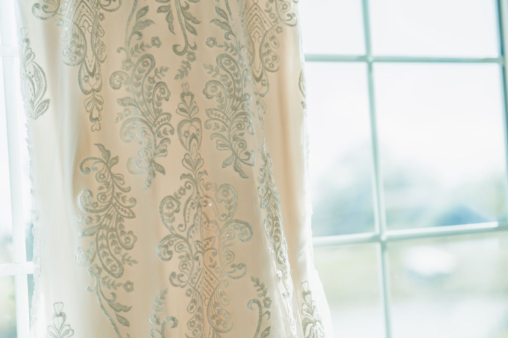 Close view of embroidered lace on a wedding gown beside a window