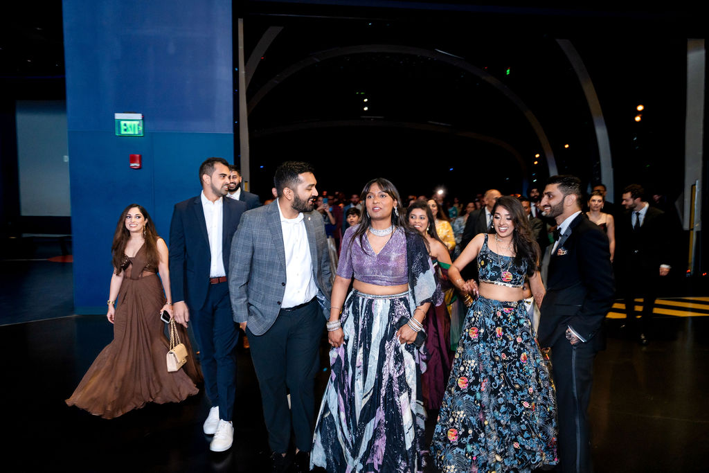 Adult wedding guests gathering in a blue-lit reception hall