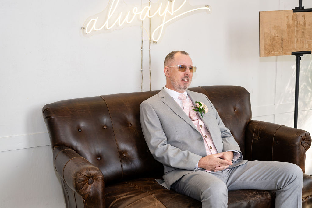 Bride’s father waiting on a leather sofa before the first look