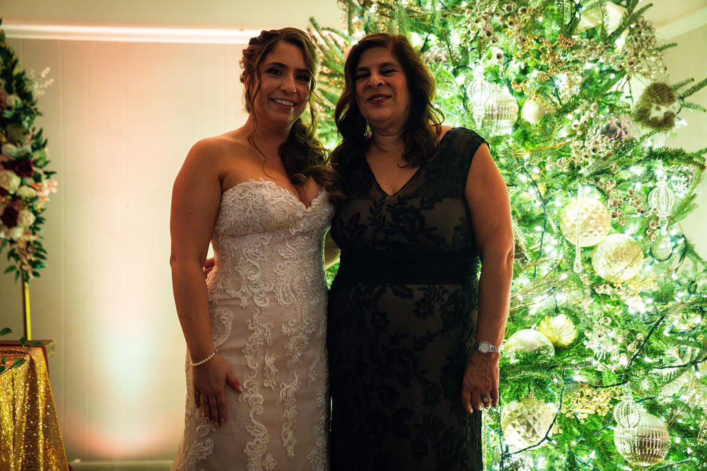 Bride posing with an adult guest beside a bright reception window