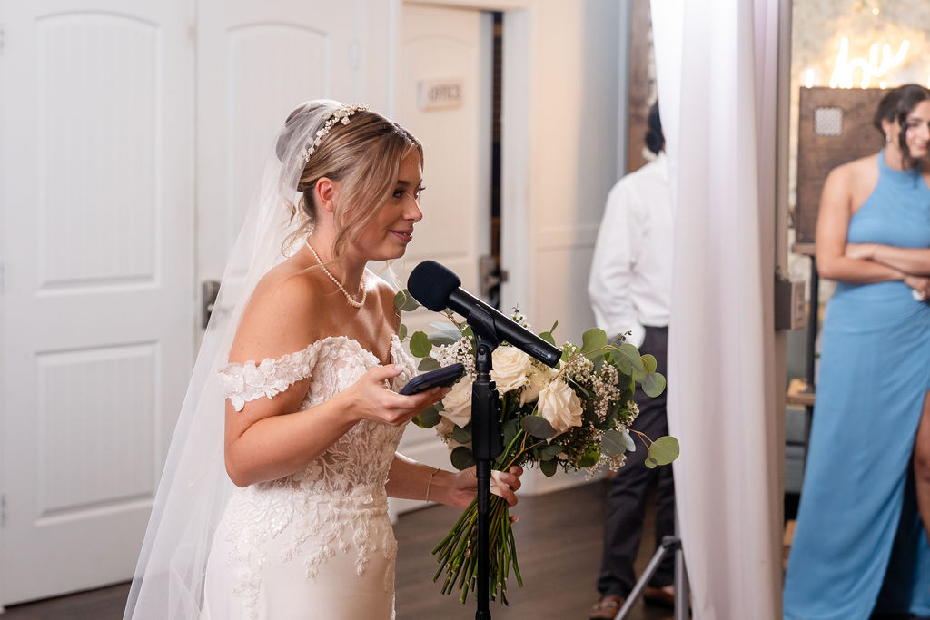 Bride speaking into a microphone while holding her bouquet