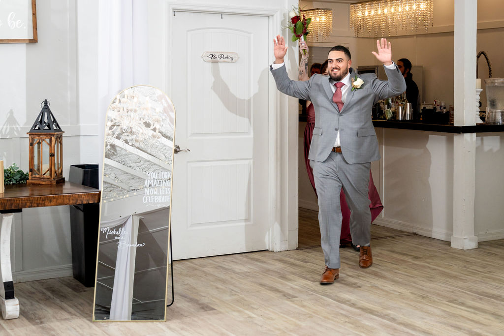 Groomsman raising his hands as he enters the reception