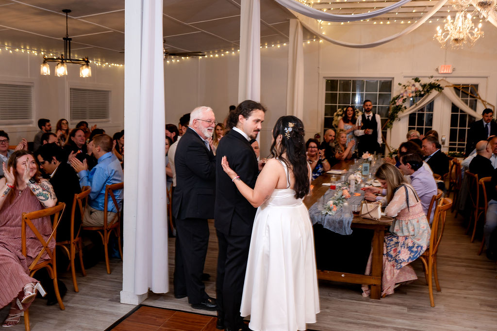 Bride and groom sharing their first dance as guests watch