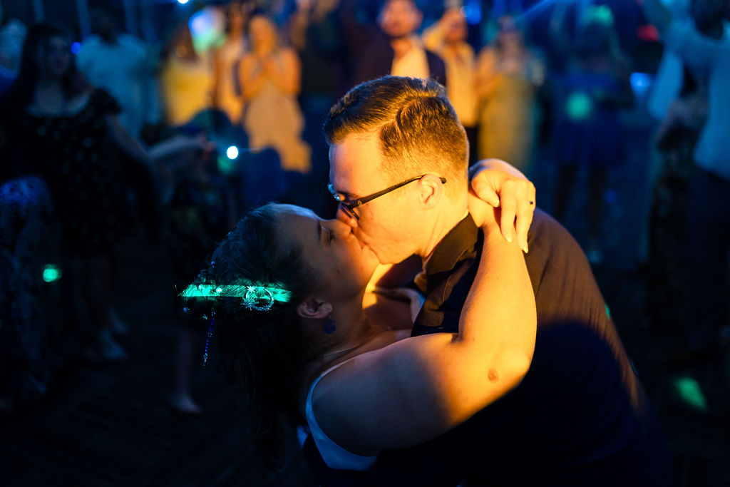 Bride and groom embracing under colorful evening reception lights