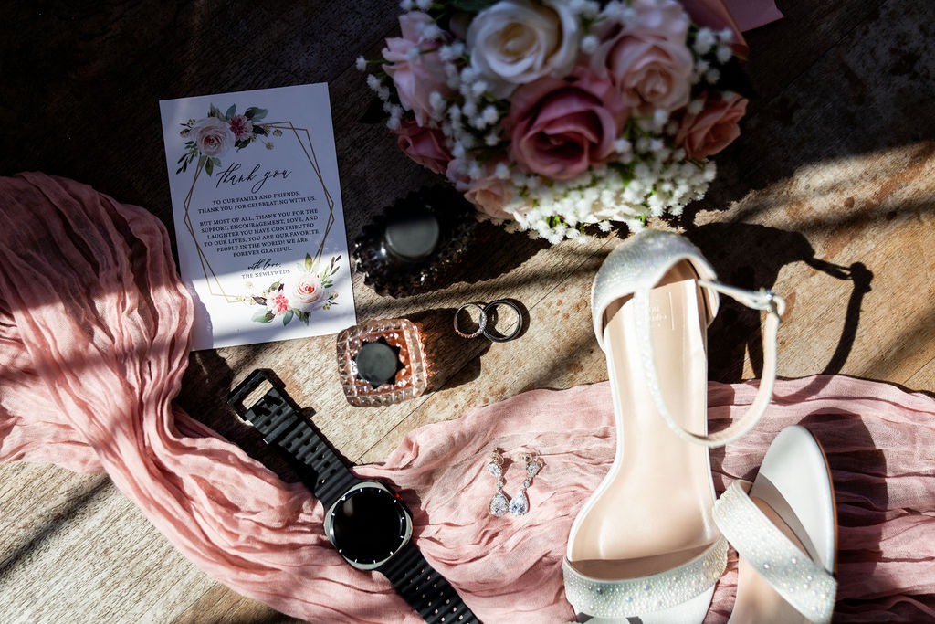 Wedding flat lay with blush fabric, white shoes, jewelry and pink flowers