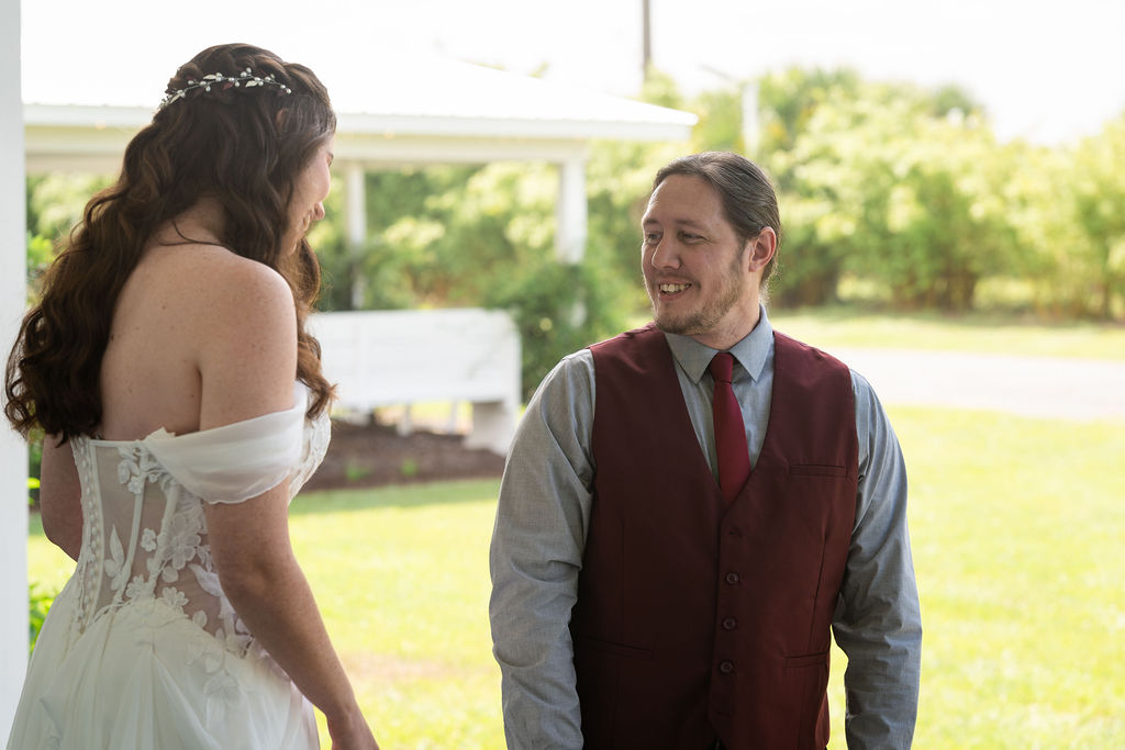 Bride and groom smiling at each other during an outdoor first look