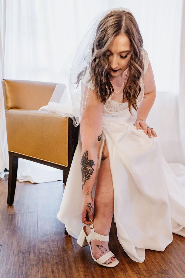 Bride fastening her white wedding shoes