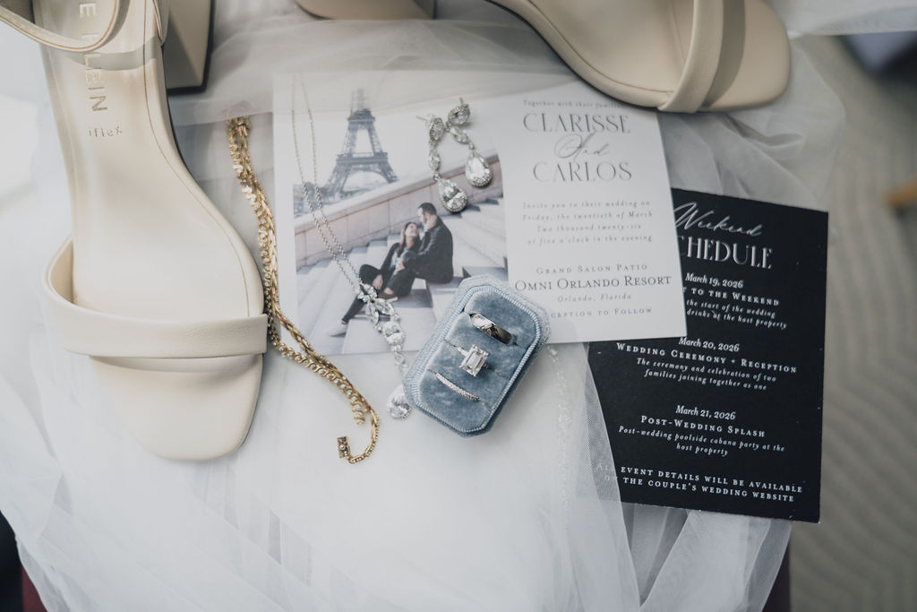 Wedding stationery, jewelry and rings arranged on white fabric