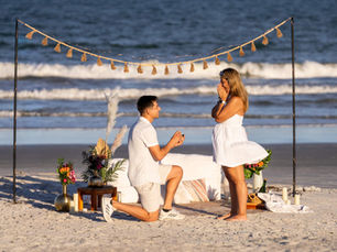 Romantic beach proposal setup during sunset with a couple embracing on the shoreline in Florida
