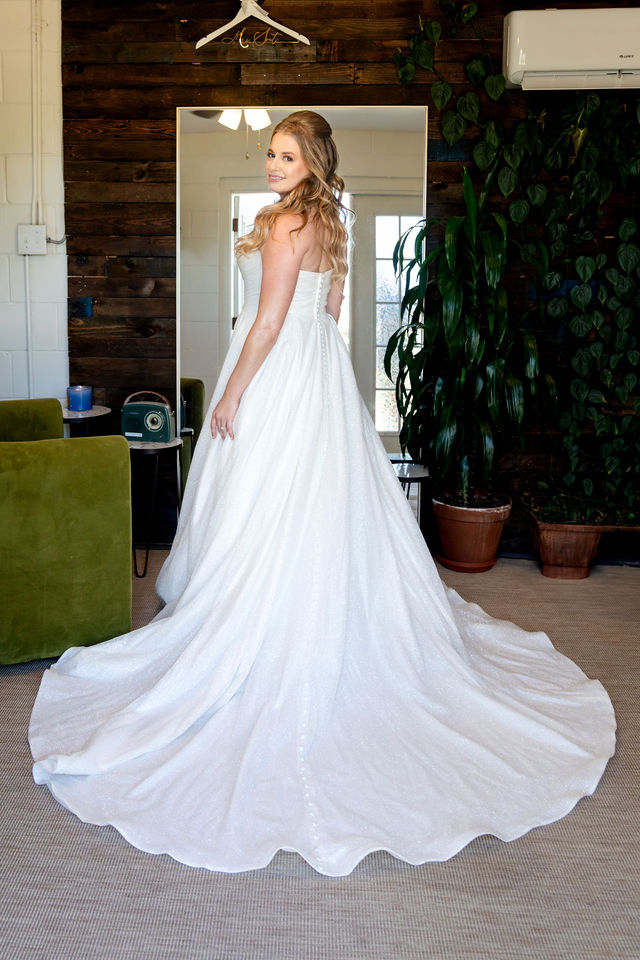 Bride looking over her shoulder with her gown train spread across the floor