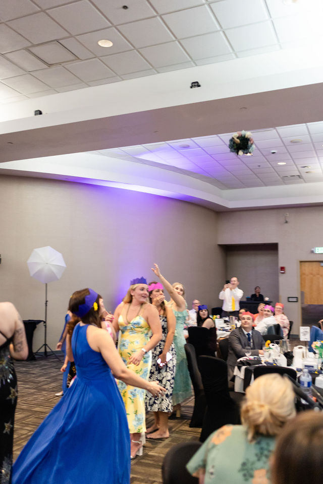 Guests reaching for the bouquet during a wedding reception