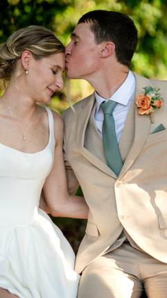 Bride and groom sharing a kiss outdoors in bright natural light