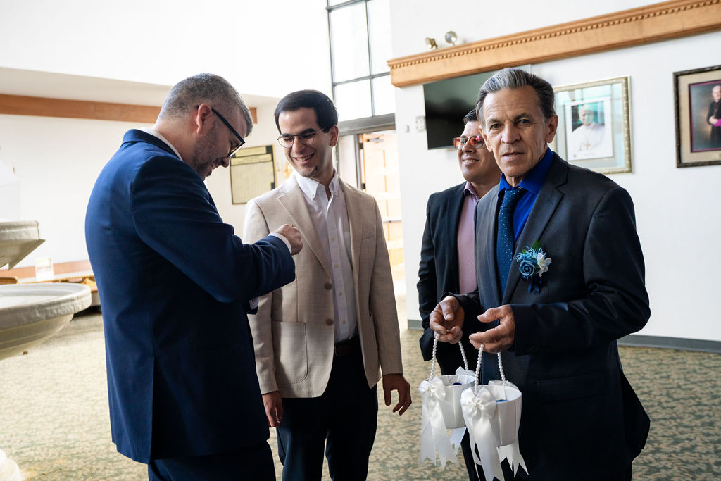 Groom and adult wedding guests chatting before the church ceremony