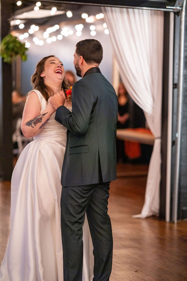 Bride laughing with the groom beneath warm reception string lights