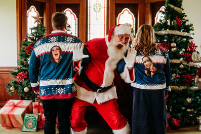 Santa standing between two people for christmas photosession