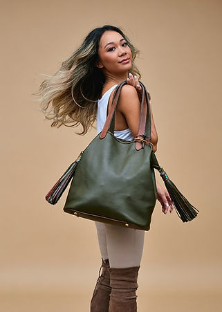 Model showing olive green box calf La Vache Safari tote with vegetable tanned buffalo and decadent olive green and light brown two-toned tassels