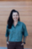 Smiling woman with tattoos in a green shirt and brown pants