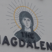 The Magdalens sign on a white wall with the saintly face image