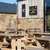 Outdoor seating area with tables and Bar in Shop sign, Whitby setting.