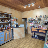 Shop interior with merchandise on shelves and display tables for sale.