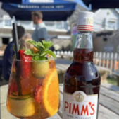 Pimm's No. 1 cocktail and bottle on a table with fruit and mint garnish.