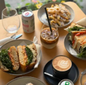 Sandwiches, pasta, and coffee on a table, with a glass of iced coffee in between.