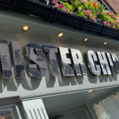 Shiny chrome sign says MASTER CHIPS, flowers above the shop front, detail view