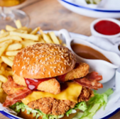 Delicious burger with fries, ketchup, and gravy, served on a white plate
